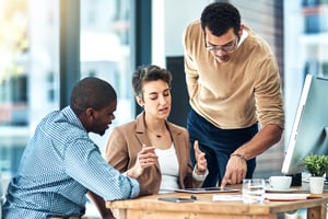 People looking at a tablet on a desk in an office.