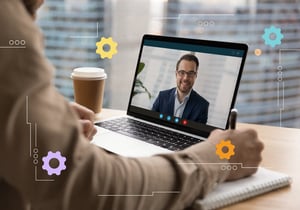 An open laptop showing a person on a video call with gear icons.