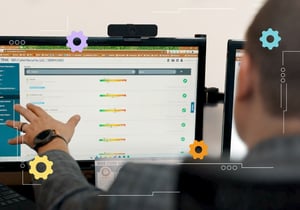A person gesturing toward a computer monitor showing TRAC cybersecurity risk management software.