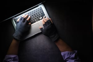 an image of a hacker typing on a laptop in a dark room.